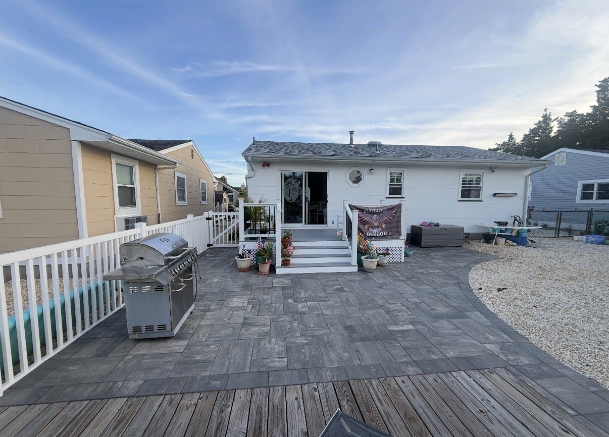 After: The finished paver patio and deck, with white railings and new steps to the slider.