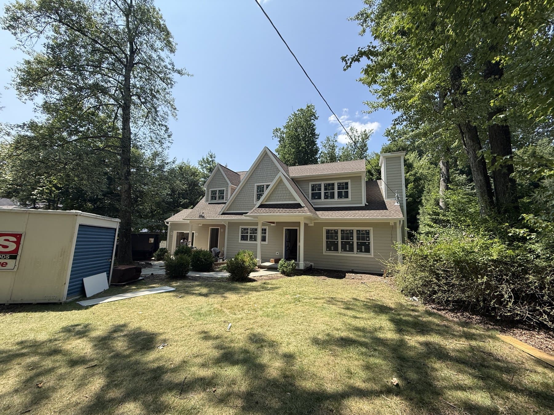 After: The finished two-story home with shingled front gables and a covered porch.