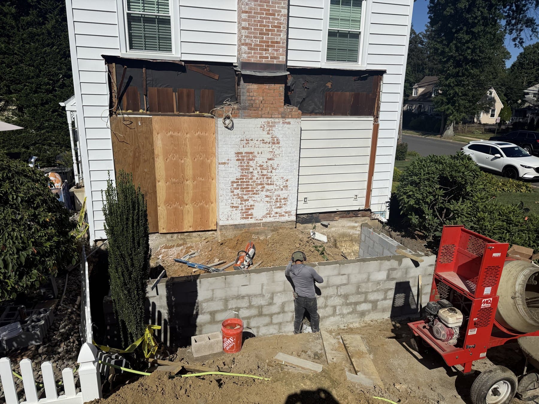During: The wall opened to the framing, with a mason laying the block foundation for the addition.