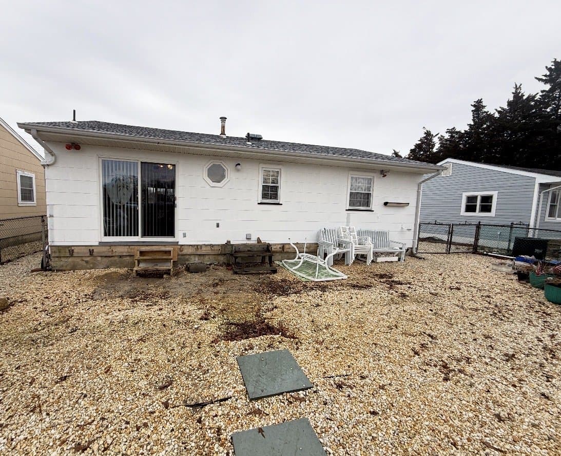 Before: The backyard covered in loose stone, with the back of the house behind it.