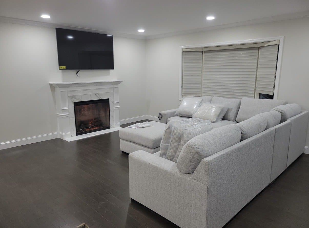 The new fireplace wall: white mantel, marble-look surround, crown molding and dark hardwood.
